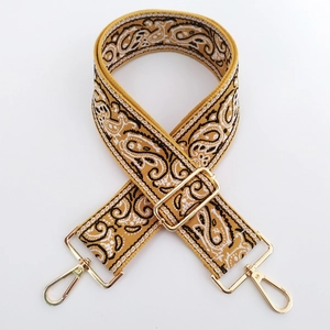 Close-up of mustard paisley embroidery wide strap with golden metal lobster clasps