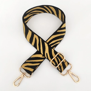 Close-up of zebra pattern nylon bag strap with polished gold-tone metal lobster clasps