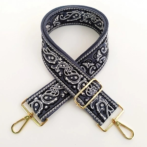 Close-up of paisley pattern wide woven shoulder strap with gold metal lobster clasps