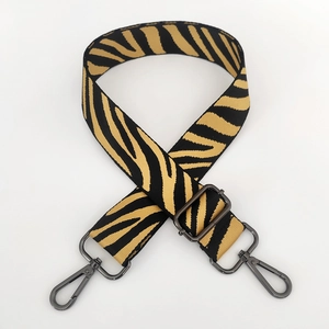 Macro detail of zebra pattern woven bag strap with charcoal gray metal lobster clasp