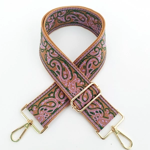 Detailed embroidery of paisley patterns on thick vintage bag strap with gold metal hooks