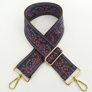 Detailed embroidery of ethnic paisley patterns on a wide crossbody bag strap with gold hooks