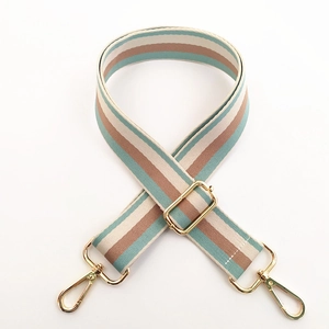Close-up of thick woven striped bag strap with adjustable gold buckle and metal hooks