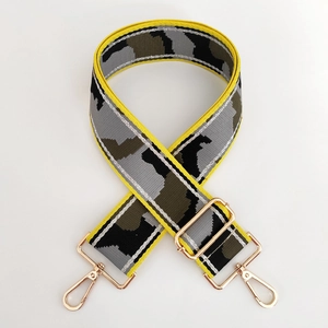 Detail of adjustable camouflage bag strap with yellow edges and gold-tone metal hooks