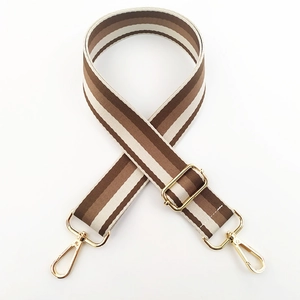 Detail showing adjustable striped nylon shoulder strap with gold metal hooks and buckle