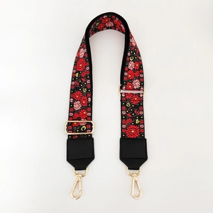 Detailed view of floral embroidered wide purse strap with golden metal lobster clasps