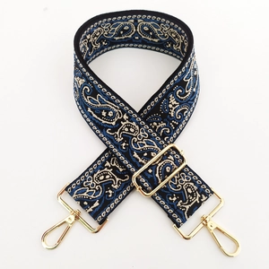 Close-up of bohemian paisley embroidery on a wide bag strap with gold metal buckles