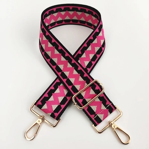 Close-up of adjustable woven purse strap with colorful geometric wave patterns and gold buckles