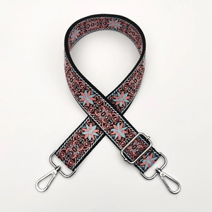 Detail view of ethnic embroidery pattern on adjustable woven crossbody bag strap