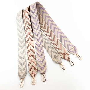 Detail of embroidered wide bag straps with arrow pattern and gold-tone metal lobster clasps