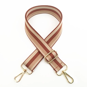 Detail of adjustable wide striped strap with golden metal clasps for crossbody bags