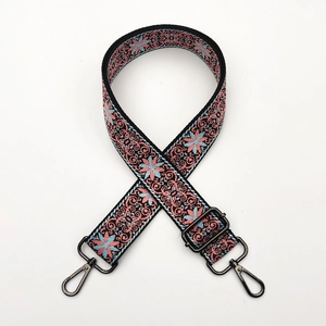 Detail of adjustable ethnic embroidery strap with pink floral patterns and metal hooks