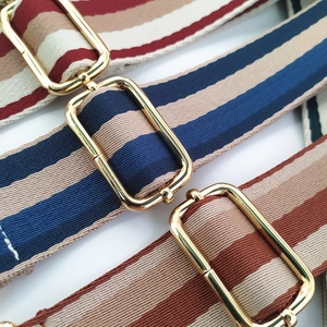 Detail of three thick striped woven shoulder straps with adjustable gold buckles
