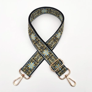 Close-up of ethnic floral embroidery pattern on adjustable bag strap with gold buckle