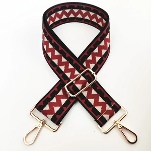 Close-up of wide adjustable woven bag strap with red and black geometric wave pattern