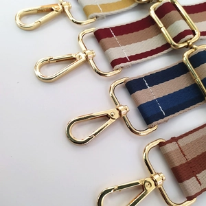 Detail of adjustable woven wide shoulder strap with colorful stripes and gold metal buckles