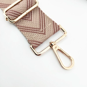 Macro view of woven geometric bag strap with premium gold swivel lobster clasp and buckle
