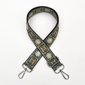 Close-up of ethnic jacquard bag strap with blue floral embroidery and silver hooks