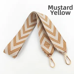 Detail of ginger yellow geometric jacquard embroidery on wide fabric bag strap with gold clasps