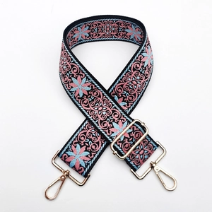 Detail of colorful floral embroidery and gold metal hooks on the wide bag strap