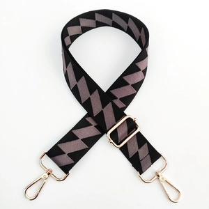Detail of adjustable wide shoulder strap with gray geometric patterns and gold metal buckles
