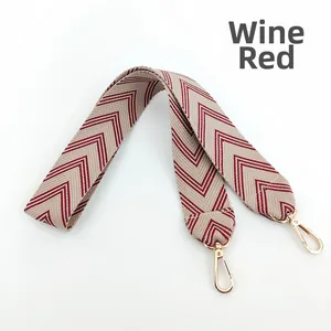 Close-up of wine red and beige herringbone woven bag strap with golden metal hooks
