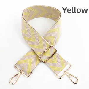 Close-up of adjustable yellow and beige chevron canvas bag strap with gold metal hooks
