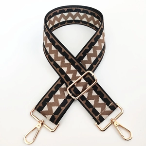 Close-up of adjustable woven canvas strap with geometric pattern and gold buckles
