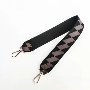 Detail view of 55cm wide bag strap with grey geometric patterns and gold lobster clasps