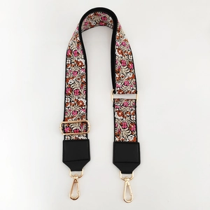 Detail of bohemian floral embroidery and golden metal hooks on a wide bag strap