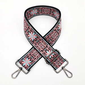 Detail of ethnic floral embroidery on a thick black bag strap with metal buckle