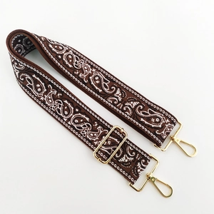 Detail of adjustable brown paisley embroidered bag strap with gold metal lobster clasps