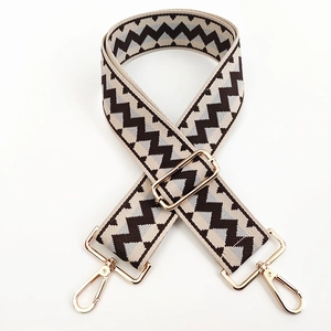 Detail of wide woven shoulder strap with zigzag pattern and golden metal buckles