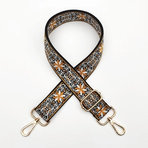 Detail of ethnic embroidered bag strap with golden metal swivel hooks and floral pattern