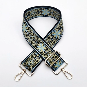 Close-up of ethnic embroidered bag strap with blue floral pattern and gold metal hardware