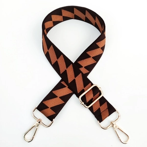 Detail of adjustable woven bag strap with brown geometric patterns and gold metal buckles