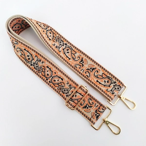 Close-up of ethnic paisley embroidered wide bag strap with gold metal hardware and adjustable buckle