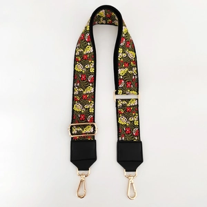 Detail of floral ethnic embroidery on black guitar strap with gold metal swivel hooks