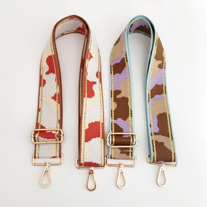 Detailed view of wide camouflage woven bag straps with gold stitching and metal clasps