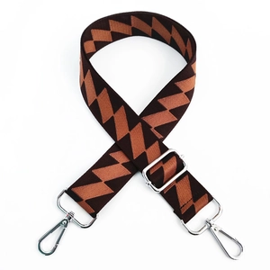 Close-up of geometric brown woven wide strap with silver swivel hooks and metal buckle