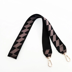 Close-up of wide woven bag strap with grey zigzag pattern and gold lobster clips