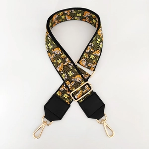 Close-up of adjustable wide woven bag strap with yellow floral embroidery and gold metal hooks