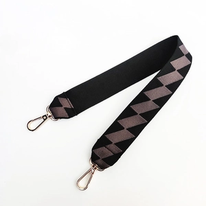Detailed view of woven geometric diamond pattern on wide bag strap with gold lobster clasps