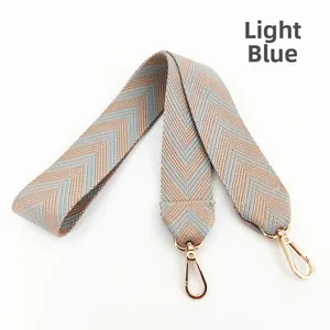 Close-up of light blue chevron woven shoulder strap with gold metal rotating hooks
