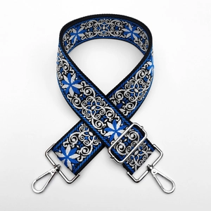Macro detail of ethnic embroidered bag strap with blue floral pattern and silver lobster hooks