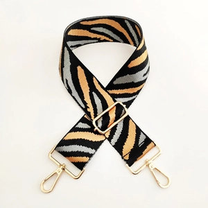 Close-up of zebra pattern wide strap with shiny gold lobster clasps and metal buckle
