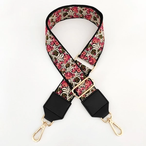 Detail of embroidered floral bag strap with pink flowers and gold metal hardware