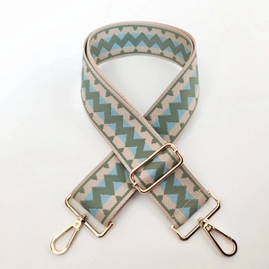 Close-up of adjustable canvas bag strap with geometric jacquard and gold metal hooks