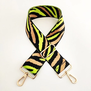 Macro detail of zebra pattern wide bag strap with shiny gold lobster clasps and buckles