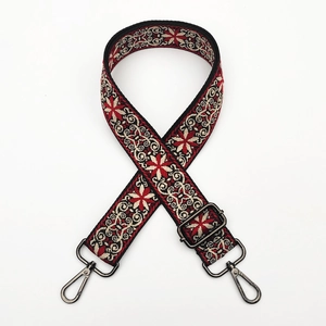 Detailed view of woven ethnic shoulder strap with red geometric pattern and metal hooks